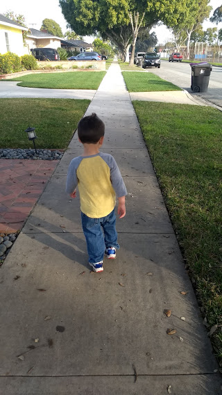 toddler walking on a sidewalk